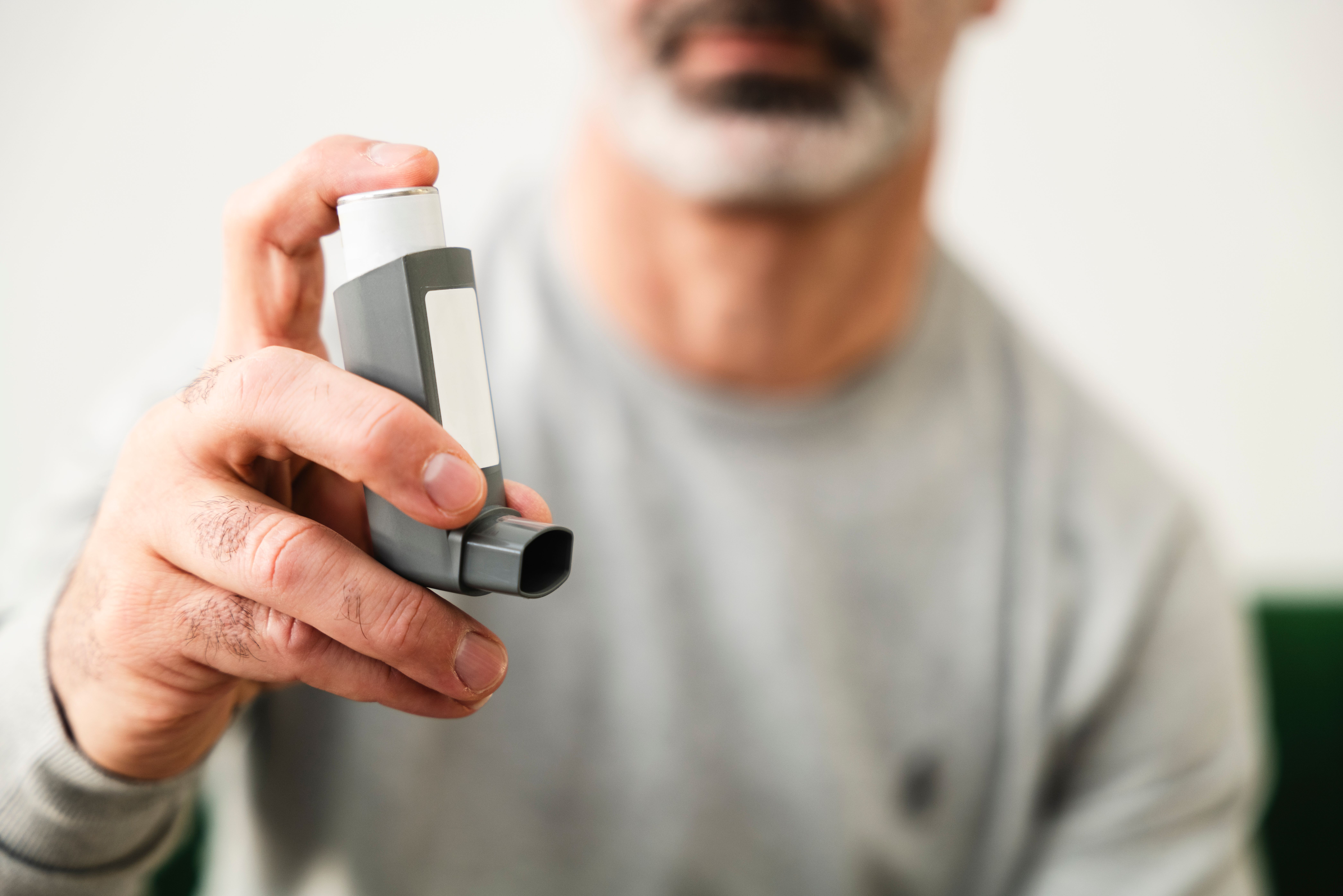 Persona utilizando un inhalador para el control del asma, salud respiratoria y calidad de vida